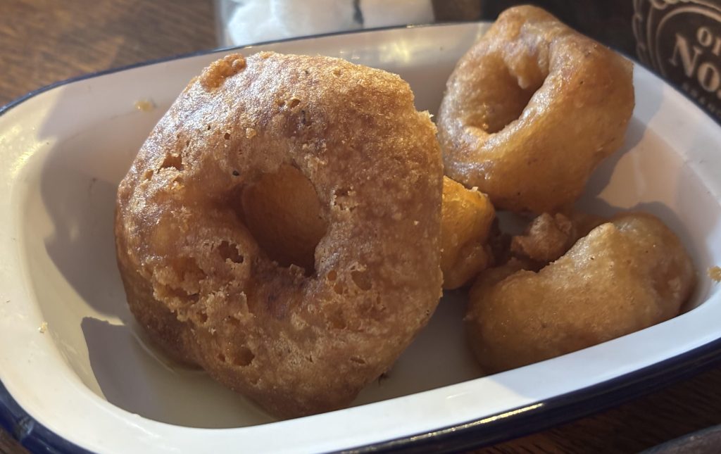 Large and small crispy beer-battered onion rings in a dish.